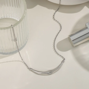 Detail shot of a silver minimalist curved bar pendant necklace with modern link chain