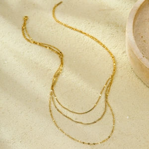Three-layer 18k gold plated stainless steel necklace on a textured stone surface