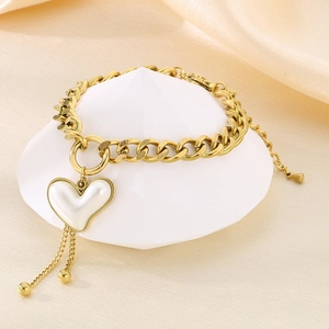 Detailaufnahme des goldenen OT-Buckle-Armbands mit weißem Herzanhänger und Fransen