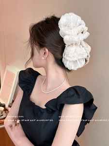 Detail of large white pleated organza hair scrunchie worn on a ponytail for volume