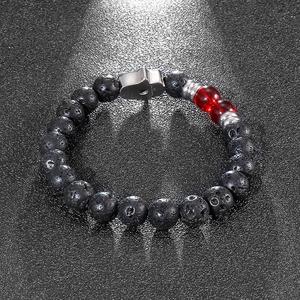 Macro detail of black lava stone beads and silver stainless steel Hamsa charm on a bracelet