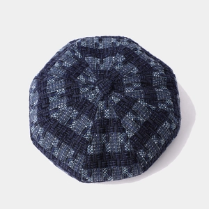 Top view of dark blue tweed beret hat with detailed woven texture and top button