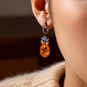 Detail of vintage teardrop earring with orange zircon and floral cluster on model