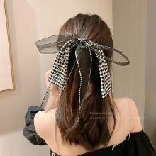 Rear view of a large black lace bow hair clip with sequins on long wavy hair