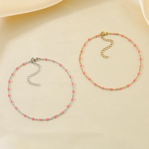 Detail of gold and silver stainless steel anklets with vibrant pink resin beads