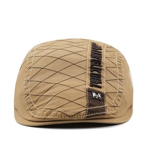 Detail of khaki cotton flat cap featuring diamond quilting and metallic M emblem logo