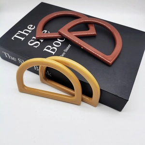 Brown and yellow D-shaped resin handles for DIY knitted handbags displayed on a book