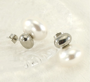 Macro shot of French vintage pearl stud earrings with polished silver metal on glass