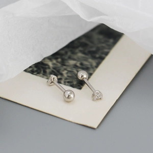 Macro shot of silver stud earring with heart diamond setting on a vintage textured card