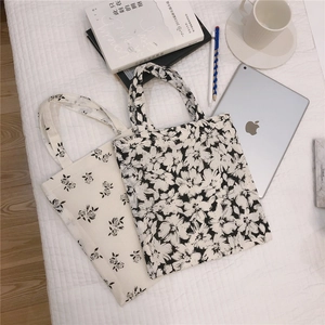 Detailed close-up of floral pattern canvas tote bags on a quilted white fabric background