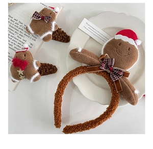 Detail view of plush gingerbread man headband and hair clips with festive red Santa hats