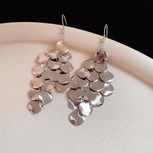 Macro shot of silver multi-layered metal sequin disc earrings on a white display plate