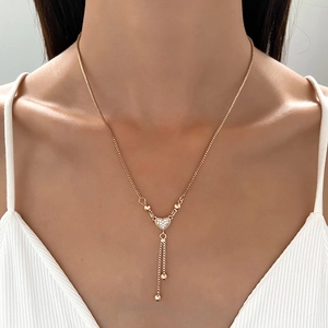 Gold-tone heart necklace with sparkling crystals and elegant chain tassels worn by model