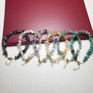 Detail of colorful crystal stone bracelets with metallic lobster clasps on textured background