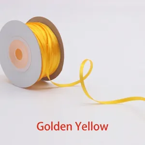 Macro detail of golden yellow satin ribbon roll on a white spool for gift wrapping