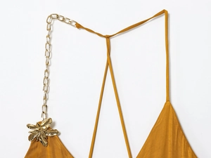 Close-up of mustard yellow satin dress with golden floral metal chain detail