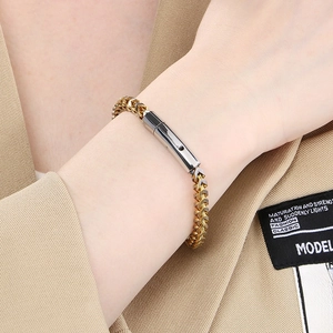 Detailed view of two-tone gold and silver stainless steel fishbone chain bracelet on wrist
