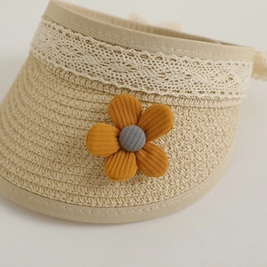 Close-up of children's straw sun hat featuring delicate white lace and a decorative flower