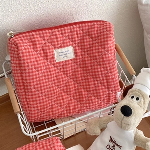 Detail of red gingham quilted cotton makeup bag with a soft texture and white brand label