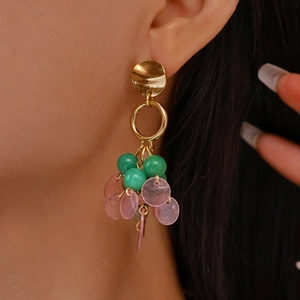Detail of vintage geometric earrings with green beads and pink shells on a model