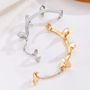 Macro detail of gothic claw ear cuffs in silver and gold with punk spike chains