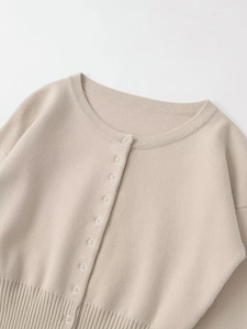 Detail der beigen Strickjacke mit feiner Textur und kleinen runden Knöpfen in Nahaufnahme