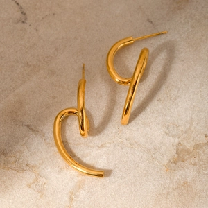 Detail of 18k gold plated stainless steel earrings with spiral design on stone surface
