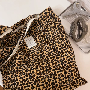 Detailed view of leopard print canvas shoulder bag with a white square logo label