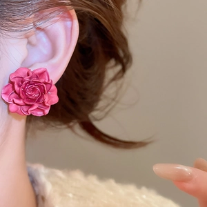 Close-up of a rose-shaped pink resin stud earring on an ear for a sweet, elegant look