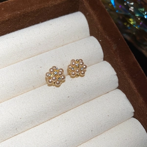 Close-up of pearl flower stud earrings with crystals on a beige velvet jewelry display