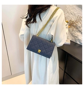 Detail of dark gray quilted denim handbag with gold chain strap and square lock clasp