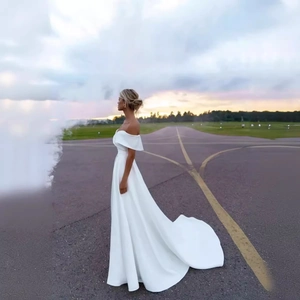 Elegant off-shoulder satin bridal gown with small train in a scenic outdoor setting