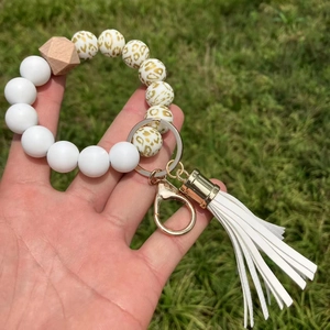 Detail of silicone beaded wristlet with sunflower print and leather tassel on grass