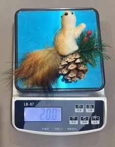 Detailed view of artificial squirrel ornament on a digital scale showing weight of 20g