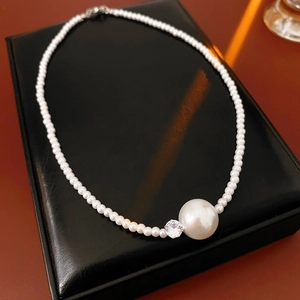 Dettaglio della collana di perle francesi con pendente grande e zircone su pelle nera