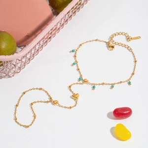 Golden heart charm bracelet with turquoise beads on a colorful decorative background