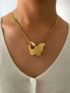 Detailed view of a gold-plated snake chain necklace with an elegant butterfly pendant on a model