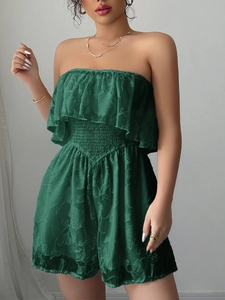 Dettaglio di un'elegante tutina verde senza spalline con pizzo floreale e vita elastica