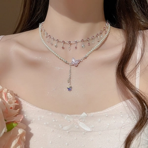 Detail of layered necklace featuring pink crystal fringe and a white pearl butterfly pendant