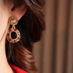 Macro view of vintage style gold earrings with amber crystals worn by a model