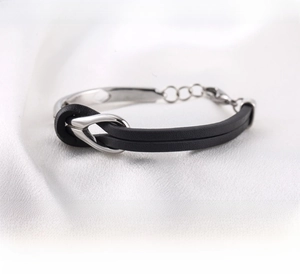 Macro shot of silver stainless steel infinity knot and black braided leather bracelet