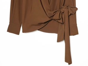 Détail du haut plissé marron caramel avec nœud latéral et texture de tissu tissé