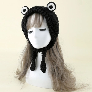 Detail of hand-knitted black frog beanie featuring large eyes and thick crochet texture