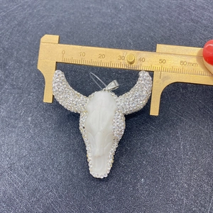 Detail view of bull skull pendant with rhinestones measured by brass caliper
