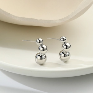 Detail of silver triple sphere earrings with polished mirror finish in a ceramic tray