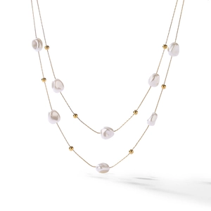 Detail of layered gold chain necklace featuring irregular white baroque pearls and beads