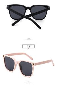 Detail of oversized computer glasses featuring a gold metal D-logo on pink and black frames