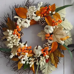 Fall wreath with white pumpkins, pine cones and maple leaves on a rustic twig base