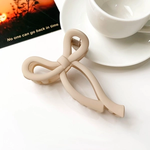 Close-up of matte beige bow-shaped hair claw clip with a soft-touch matte finish