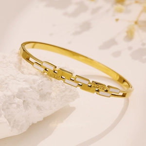 Macro detail of gold-plated titanium bracelet featuring white enamel and LOVE engraving
